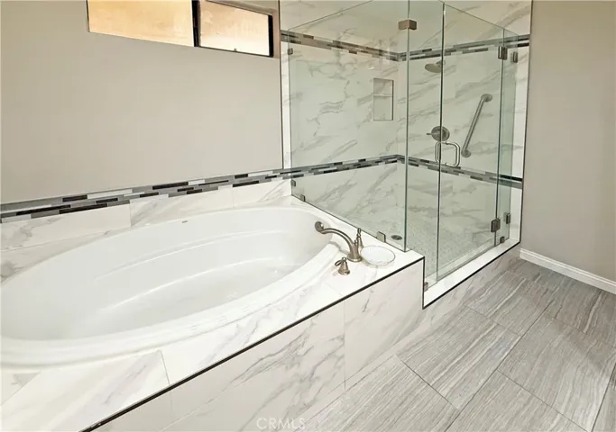 Primary suite bathroom has romantic soaking tub and separate shower with designer tile surround - Carrera marble type