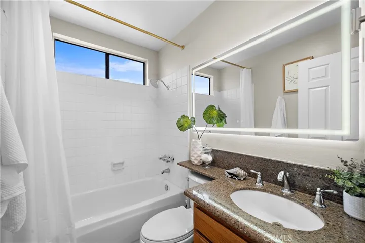 Hall bathroom boasts Led touch-light-up mirror and vanity with granite countertop, plus tub/shower combo