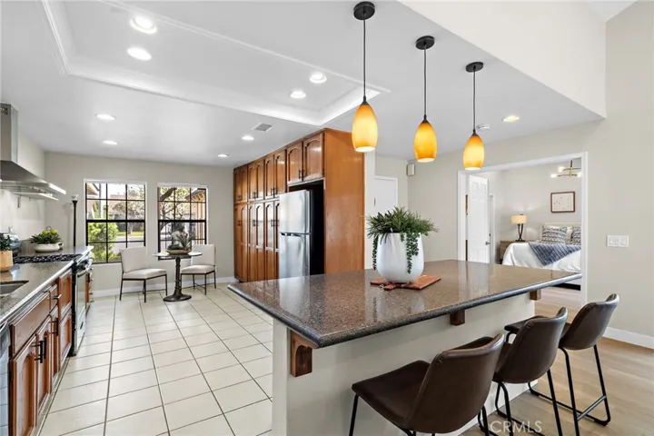 Remodeled gourmet kitchen with granite countertops, tile flooring, an abundance of cabinetry, center island with breakfast bar, eat-in breakfast nook area