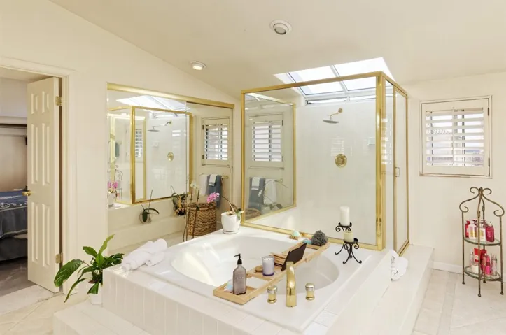 Ensuite bathroom with a stall shower, a garden tub, light tile patterned floors, a skylight, and vaulted ceiling