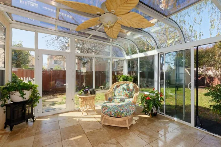 Sunroom with a ceiling fan and a wood stove
