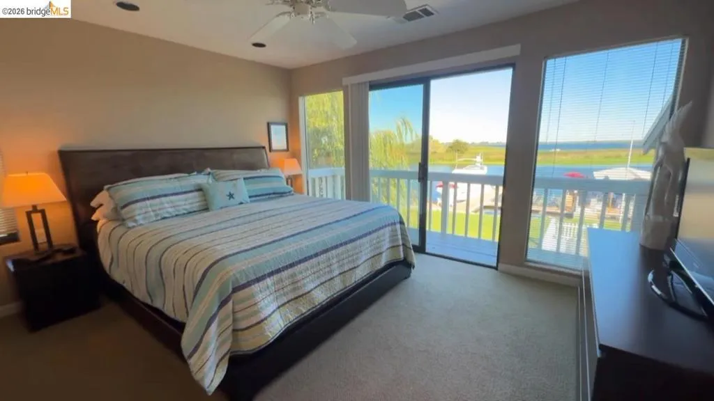 Bedroom with access to outside, dark colored carpet, and ceiling fan