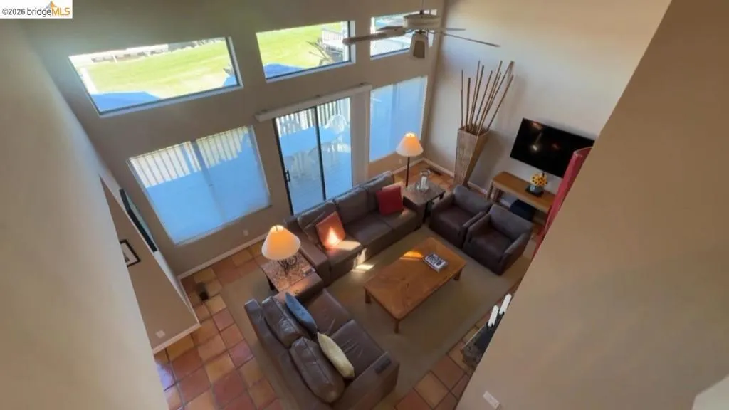 Living area featuring a high ceiling, tile patterned flooring, and a ceiling fan