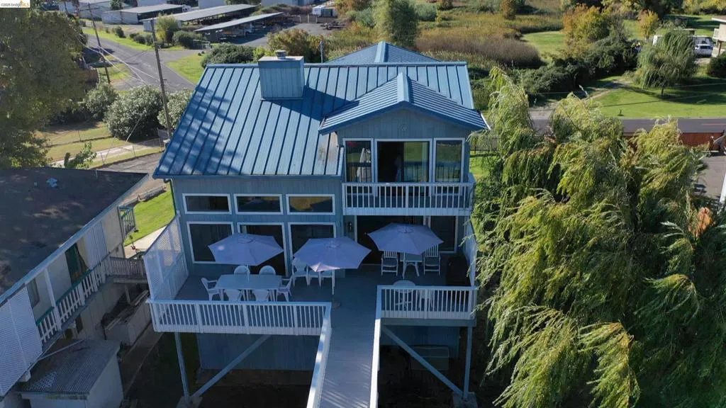 Back of property featuring outdoor dining area, a chimney, a balcony, a standing seam roof, and a patio