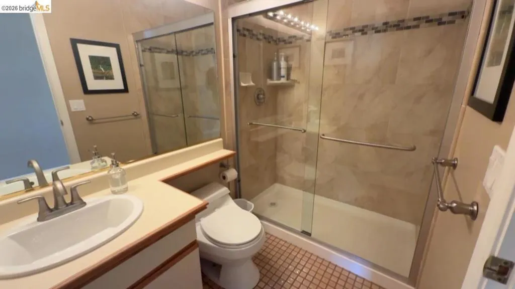 Full bath with vanity, a stall shower, and tile patterned flooring
