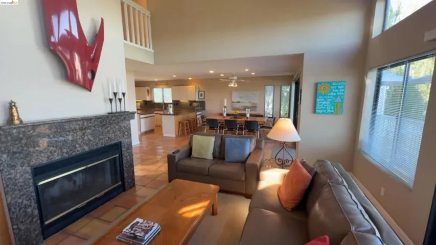 Living area featuring a tiled fireplace, ceiling fan, light tile patterned floors, and a high ceiling