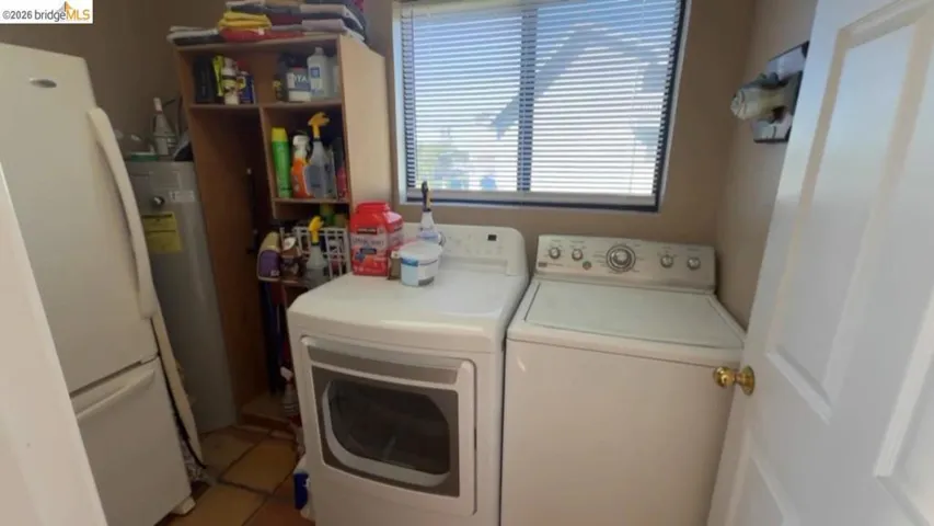 Laundry room with light tile patterned floors, independent washer and dryer, and water heater
