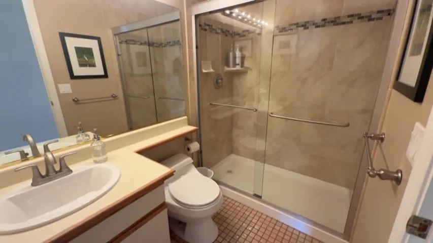 Full bath with vanity, a stall shower, and tile patterned flooring