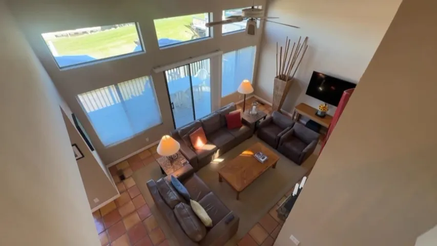 Living area featuring a high ceiling, tile patterned flooring, and a ceiling fan