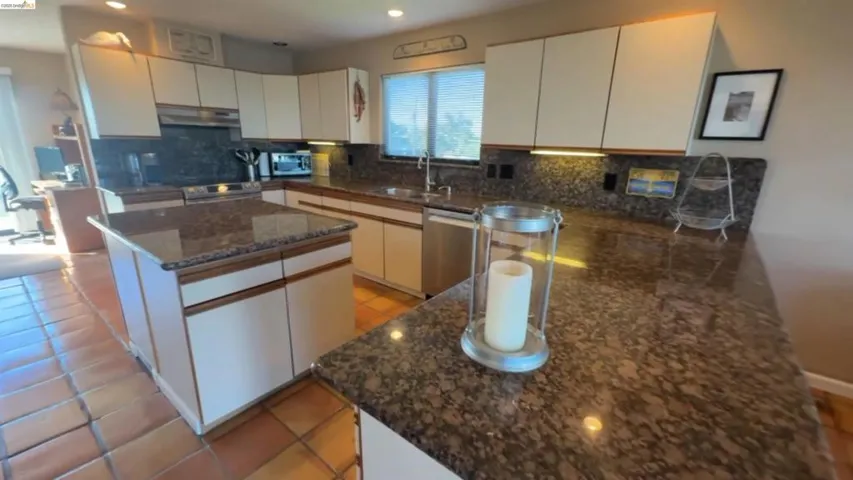 Kitchen featuring tasteful backsplash, white cabinets, stainless steel appliances, dark stone countertops, and recessed lighting