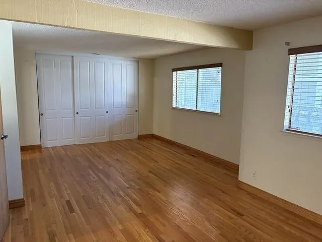 Unfurnished bedroom with a textured ceiling, light wood finished floors, and a closet