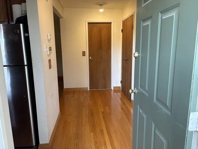 Corridor featuring light wood-style flooring and baseboards