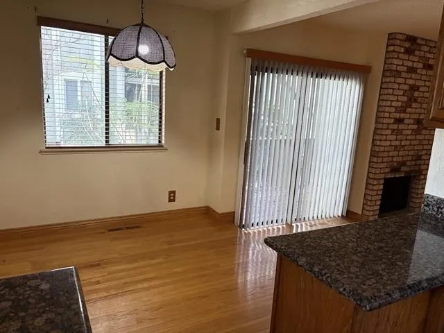 Unfurnished dining area featuring a fireplace and dark wood-style flooring