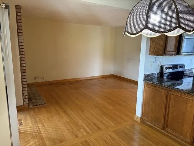 Unfurnished dining area featuring light wood-type flooring and baseboards