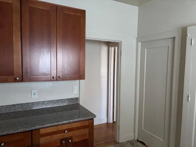 Kitchen featuring dark stone counters and dark wood finished floors