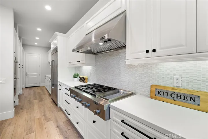 Premium kitchen finishes including custom cabinets, statement range hood, dual built-in ovens, and integrated refrigerator
