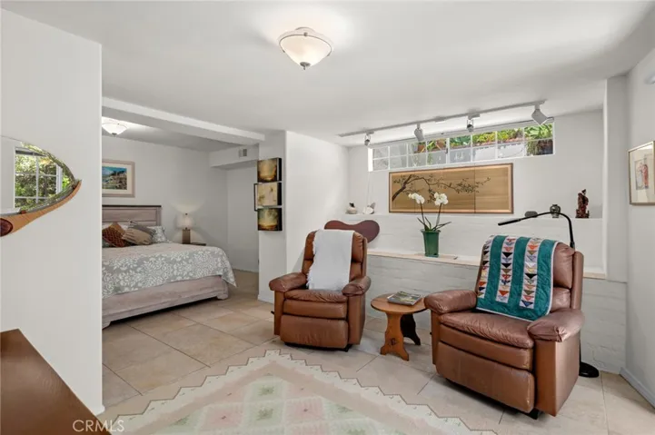 A main-level bedroom allows for single-level living and connects to an additional room that can serve as a den, media room, or family room, with access to a spacious finished storage area.