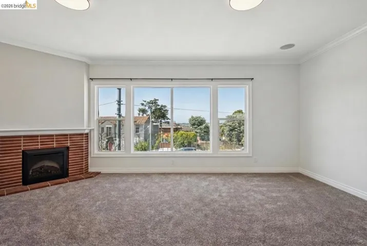Unfurnished living room with carpet, crown molding, and a fireplace