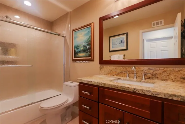 Upstairs full guest bathroom with granite counter and cherry wood vanity storage.