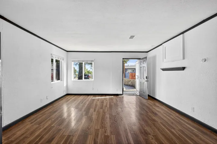 Spare room with a textured wall, dark wood-style flooring, a textured ceiling, and crown molding