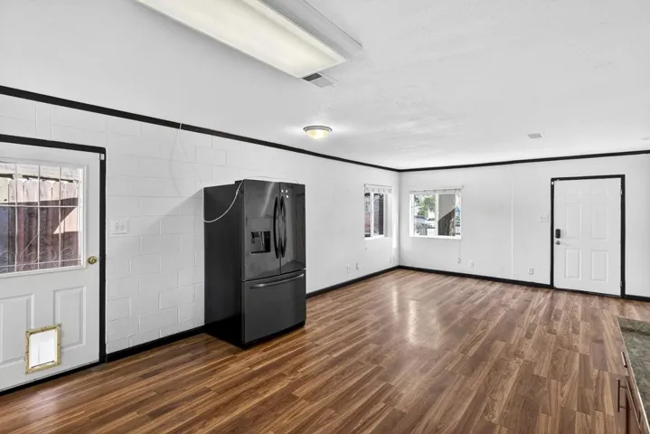 Kitchen featuring black refrigerator with ice dispenser, dark wood-type flooring, and ornamental molding
