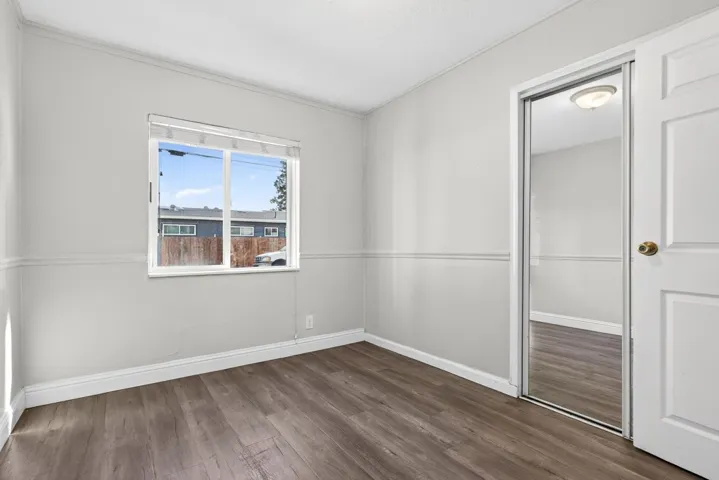 Spare room with dark wood-style flooring and baseboards