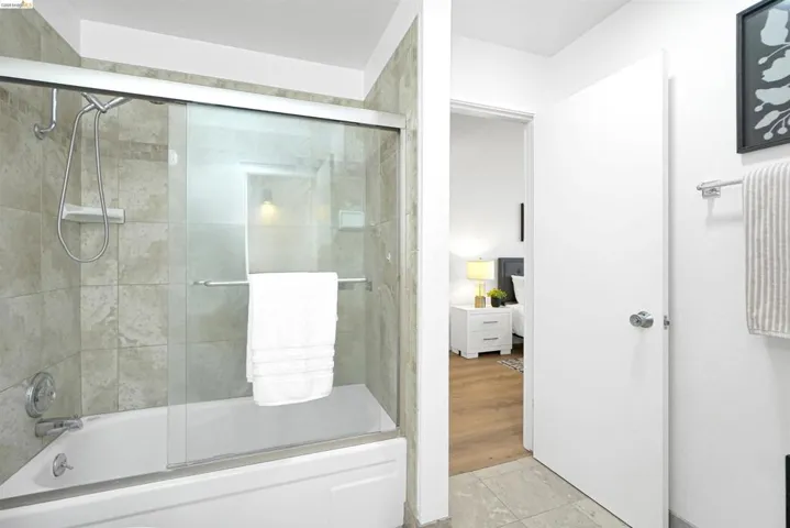 Full bath with shower / bath combination with glass door and light tile patterned flooring