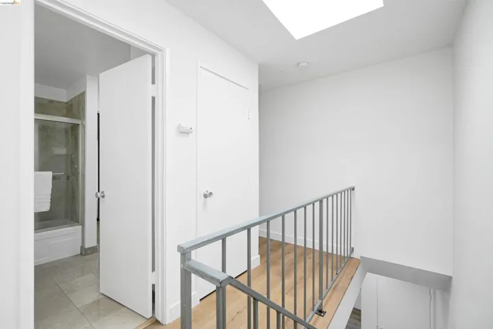 Hallway featuring an upstairs landing, a skylight, and light tile patterned flooring