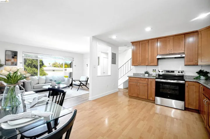 Kitchen featuring electric stove, wood finish cabinets, light stone countertops, light wood-style floors, and recessed lighting