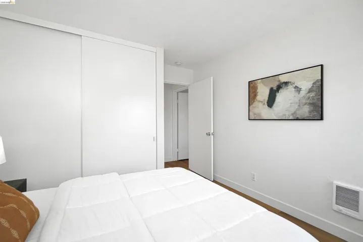 Bedroom with wood finished floors, heating unit, and a closet
