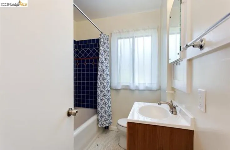 Bathroom featuring vanity, shower / bath combo, and tile patterned flooring