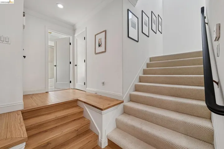 Staircase with ornamental molding, hardwood / wood-style floors, and recessed lighting