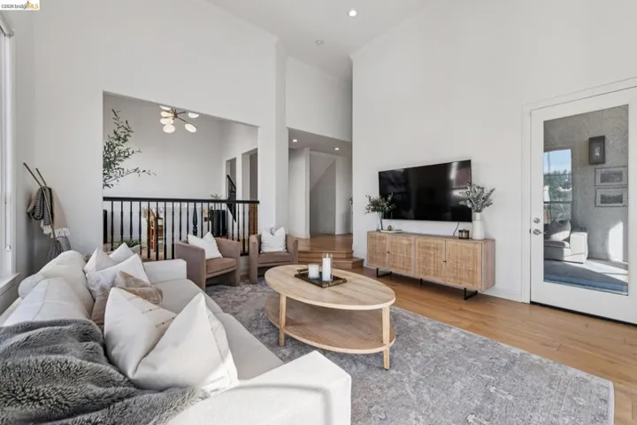 Living room featuring wood finished floors, recessed lighting, a high ceiling, and ornamental molding