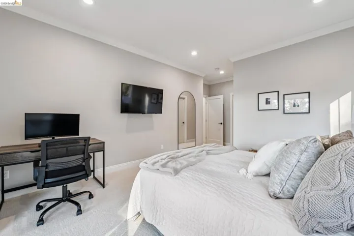 Carpeted bedroom with crown molding, a desk, recessed lighting, and arched walkways