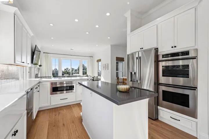 Kitchen featuring white cabinets, stainless steel appliances, light wood-style floors, recessed lighting, and a center island