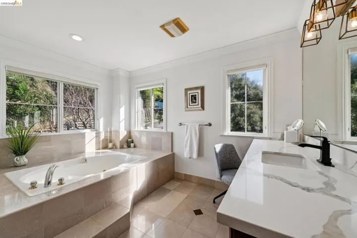 Full bath with vanity, a whirlpool tub, light tile patterned floors, and crown molding