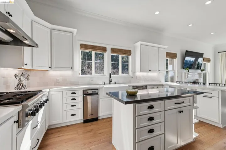 Kitchen featuring white cabinets, light wood finished floors, ornamental molding, stainless steel gas stovetop, and a center island