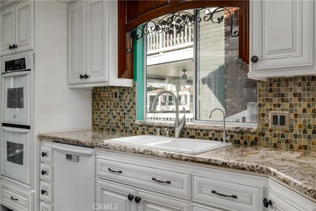 Bright kitchen with granite counters, designer backsplash, and picturesque window views bringing natural light into the heart of the home.