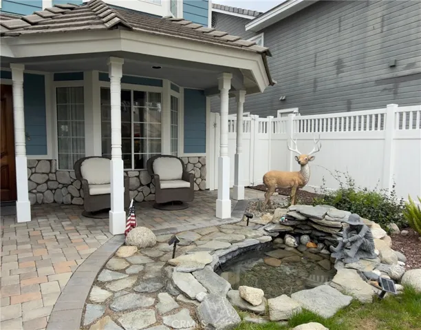 Enjoy a resort-style entry with a charming courtyard featuring custom stonework and a tranquil pond. The dining room overlooks the serene water feature, creating a peaceful indoor-outdoor ambience. Covered patio with elegant columns, stacked stone accents and an inviting seating area on a culdesac.