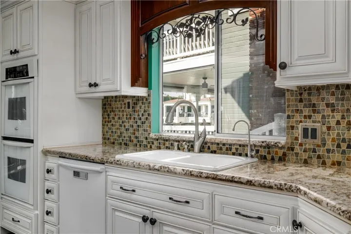 Bright kitchen with granite counters, designer backsplash, and picturesque window views bringing natural light into the heart of the home.