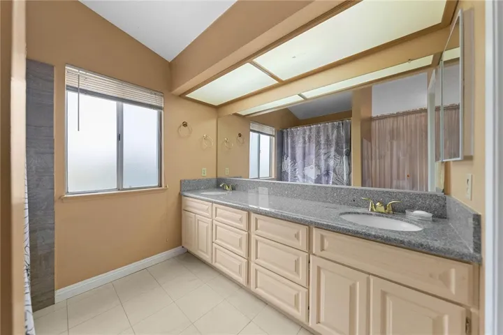 Spacious bath with long dual-sink vanity, ample cabinetry, and oversized mirror with bright overhead lighting.
