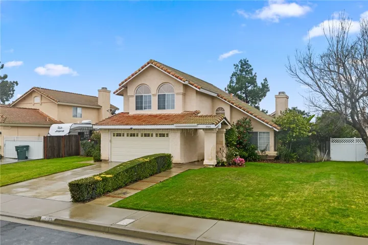 Street-side view highlighting the home’s frontage, driveway, and tidy landscaping with a generous lawn area.
