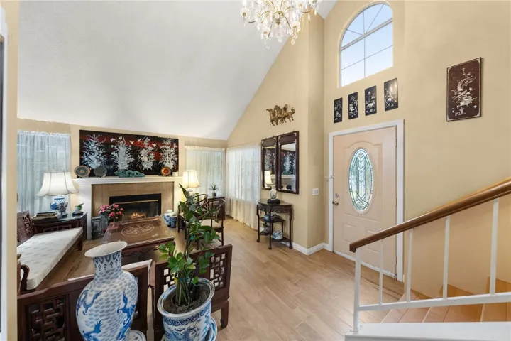 Dramatic vaulted ceilings and an arched window create an airy first impression, with a cozy fireplace as a focal point.