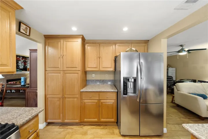Wall of cabinetry with pantry and counter workspace alongside a stainless steel refrigerator for extra storage and prep space.