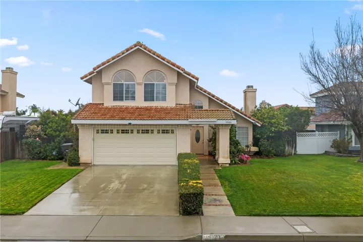 Classic two-story exterior with an attached two-car garage, arched window accents, and a spacious front lawn.