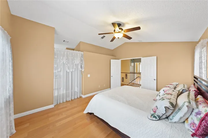 Spacious retreat with vaulted ceilings, ceiling fan, and wood flooring, plus convenient access to the upstairs hall.
