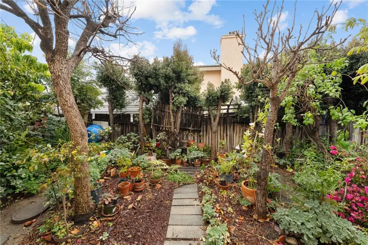 Cozy garden corner with stepping-stone path and abundant container plantings—ideal for a potting/gardening area.
