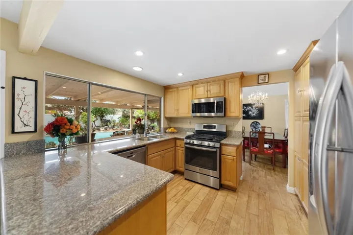 Bright kitchen with granite countertops, generous cabinetry, and stainless steel appliances, plus a large window framing the backyard/pool view.

