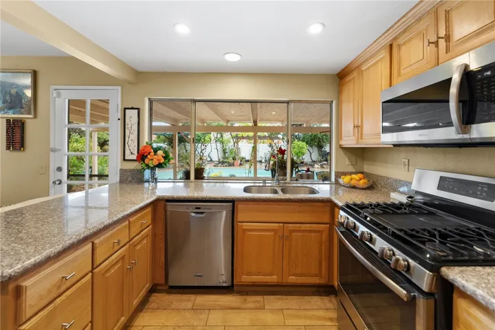 Efficient work space with granite counters, ample storage, and stainless steel range/microwave, plus a window view to the covered patio and pool.