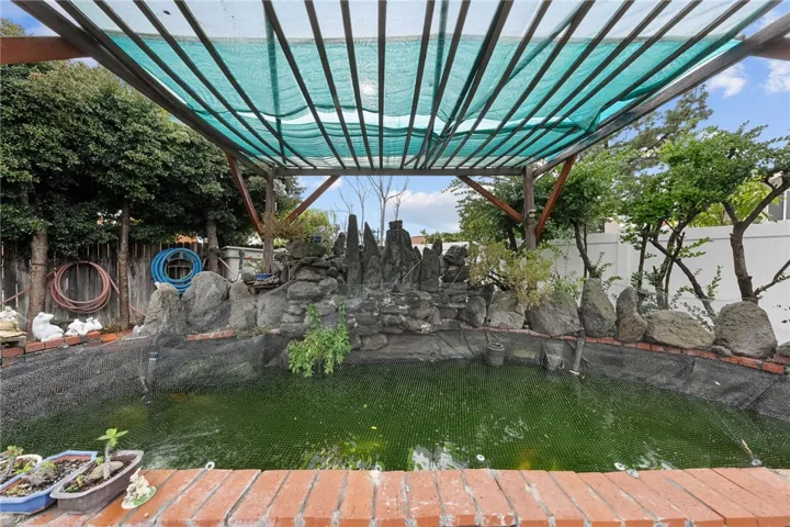 Backyard koi pond with rock landscaping and shade structure overhead—great as a tranquil garden focal point.